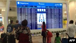 Passengers look at the departures announcement board at Dubai airport a day after an Emirates plane caught fire during a crash-landing, on August 4, 2016. 