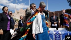 Navajo Nation President Ben Shelly (L) puts a blanket on the shoulders of U.S. Interior Secretary Sally Jewell after a ceremonial signing of a record multi-million-dollar settlement, in Window Rock, Arizona, at the Navajo Nation, Sept. 26, 2014.