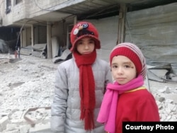Nour and Alaa stand in the rubble of their hometown in Eastern Ghouta, Feb. 23, 2018.