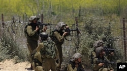 Israeli soldiers take aim next to the Syrian-Israeli border fence near the Druze village of Majdal Shams in the Golan Heights, June 5, 2011