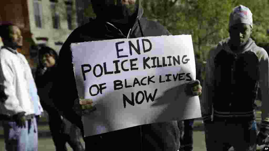 Un manifestant tient un écriteau protestant contre la mort en garde à vue d’un jeune noir, devant le poste de police de district de l'Ouest du Service de police de Baltimore, le 23 avril 2015 à Baltimore.