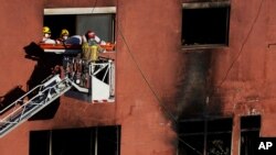 Firefighters load the body of a dead person into a crane after a fire on a building in Badalona, Barcelona, Spain, Dec. 10, 2020. 