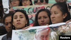 FILE - Friends and relatives hold a photograph of Efrain Segarra, who was kidnapped near the Colombian border with Ecuadorean journalists Paul Rivas and Javier Ortega (both not pictured), in Quito, Ecuador, April 1, 2018.