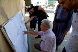 Iraqi Kurds search for their names on polling center lists during parliamentary elections in Irbil, Iraq, Sept. 30, 2018.