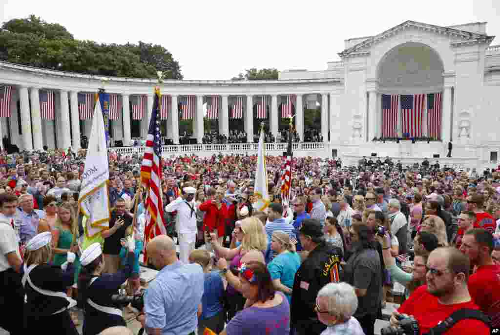 Members of the audience stand as flag bearers walk into the Memorial Amphitheater in Arlington National Cemetery in Arlington, May 29, 2017, to begin the Memorial Day ceremony.