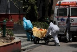 Health workers in personal protective suits ferry the body of a man who died of COVID-19 on a handcart for cremation in New Delhi, India, May 28, 2020.