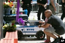 Police officer Anthony Seda, holds his daughter Penelope, 2, while paying his respects outside the 46th Precinct in the Bronx borough of New York, July 5, 2017. A police officer from the 46th Precinct was shot to death early Wednesday.