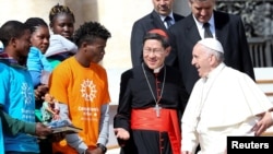 Pope Francis meets Cardinal Luis Antonio Tagle (C) and a group of migrants during the Wednesday general audience in Saint Peter's Square at the Vatican, Sept. 27, 2017. 