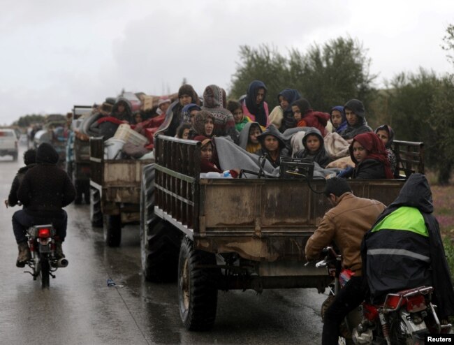 People sit in a truck with their belongings in the north east of Afrin, Syria, March 15, 2018.