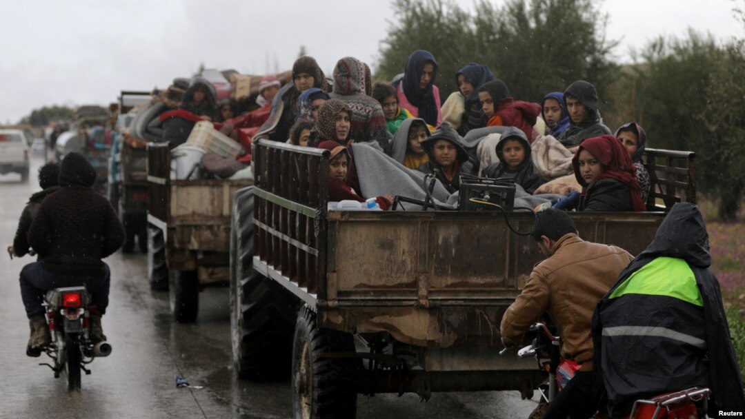 People sit atop a trailer with their belongings fleeing a Turkish offensive in Syria's Afrin region, March 15, 2018. 