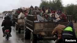 People sit atop a trailer with their belongings fleeing a Turkish offensive in Syria's Afrin region, March 15, 2018. 