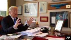 FILE - Then-Republican presidential candidate Donald Trump gestures as he speaks during an interview in his office at Trump Tower in New York, May 10, 2016. In sharp contrast to Obama, Trump relies on traditional newspapers and magazines for news and prefers old-style communication over digital methods which he deems vulnerable.