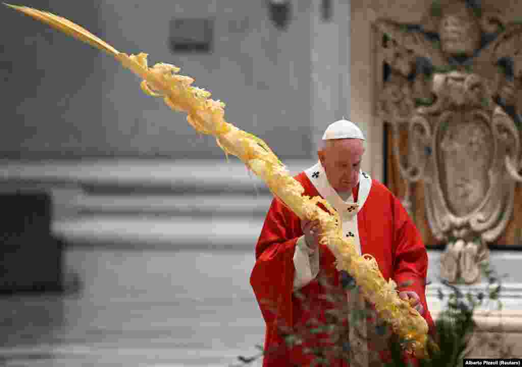 Pope Francis holds a palm branch as he leads Palm Sunday Mass in St. Peter&#39;s Basilica without public participation due to the spread of coronavirus disease (COVID-19), at the Vatican.