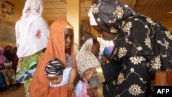 A health worker (R) vaccinates a child at a public health center where children are being vaccinated against polio in Kano, northern Nigerian, on February 13, 2013.