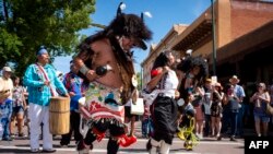 FILE - The Serpent Trail, a group of dancers from the Ohkay Owingeh Pueblo, performs during the 98th annual Santa Fe Indian Market, Aug. 18, 2019. The market hosts 1,200 Native American artists yearly, drawing crowds of up to 150,000.