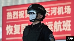 2020年4月8日武漢城市解封，天河國際機場內一名戴著口罩的警察站在標語牌前。