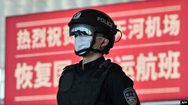 2020年4月8日武汉城市解封,天河国际机场内一名戴着口罩的警察站在标语牌前。