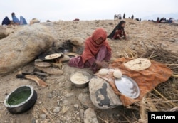 An internally displaced Afghan woman who fled from recent conflict cooks bread outside a shelter in Khogyani district of Nangarhar province, Afghanistan, Nov. 28, 2017.