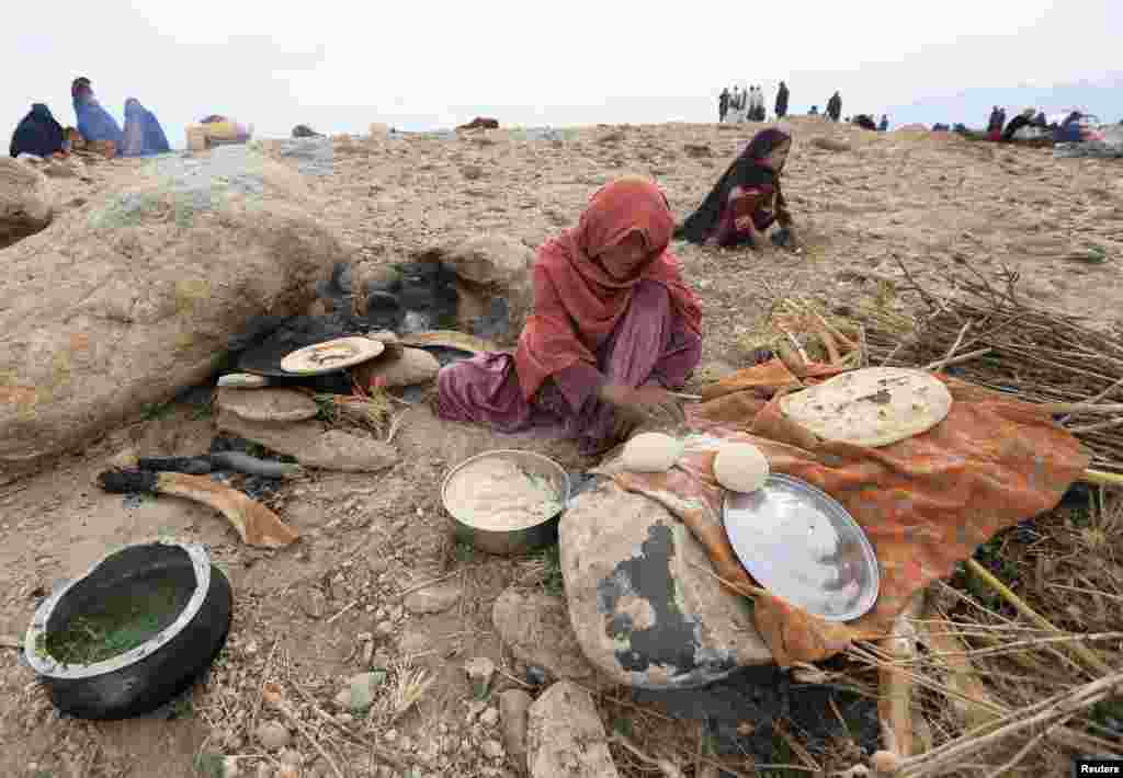 An internally displaced Afghan woman who fled from recent conflict cooks bread outside a shelter in Khogyani district of Nangarhar province, Afghanistan. Nov. 28, 2017.