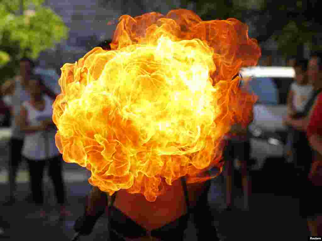 A street performer breathes fire on the eve of the feast day of the town's patron Saint Rita in Paranaque city, metro Manila, Philippines, May 17, 2014.