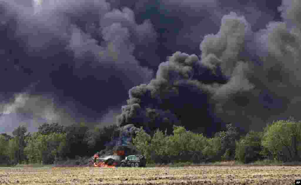 Unmarked military vehicles burn on a country road in the village of Berezove, eastern Ukraine, after a clash between pro-government troops and Russian-backed separatist militia.