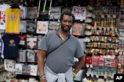 Paul Tomo poses for a photo in front of a souvenir stand in Westminster in London, Wednesday, July 22, 2020. "Two things, if we really needed them why weren't they introduced in the beginning," he said.