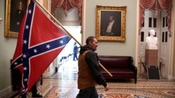 Un simpatizante del presidente Donald Trump porta una bandera de los confederados en el segundo piso del Capitolio, luego de irrumpir con violencia al edificio. Miércoles 6 de enero de 2021.