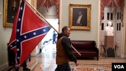 Un simpatizante del presidente Donald Trump porta una bandera confederada en el segundo piso del Capitolio, luego de irrumpir con violencia al edificio, el 6 de enero de 2021..