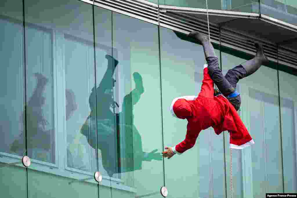 Seorang penghibur yang menyamar sebagai Sinterklas turun dari gedung rumah sakit anak di Ljubljana, Slovenia, 22 Desember 2021. (Foto: AFP)