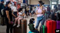 Para turis mengenakan masker di bandara di tengah pandemi Covid-19 (foto: ilustrasi). 