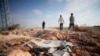 Hombres palestinos caminan hacia un cráter y escombros causados ​​por un artefacto explosivo improvisado que apuntó a un jeep militar israelí, en la ciudad palestina del norte de Yenín, en la Cisjordania ocupada por Israel, el 27 de junio de 2024.