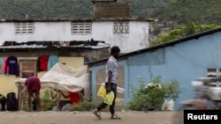 FILE - A man carries containers filled with gasoline to sell on the streets in Cap-Haitien, Haiti, April 29, 2024. 