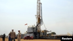 Workers are seen at an oil exploration site in Bulisa district approximately 244km (152 miles) North-West of Kampala, January 20, 2012. 