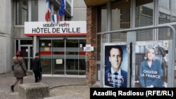 Posters of presidential election candidates Emmanuel Macron and Marine Le Pen are seen outside a polling station during the second round of 2017 French presidential election in Vaulx-en-Velin, France, May 7, 2017. 