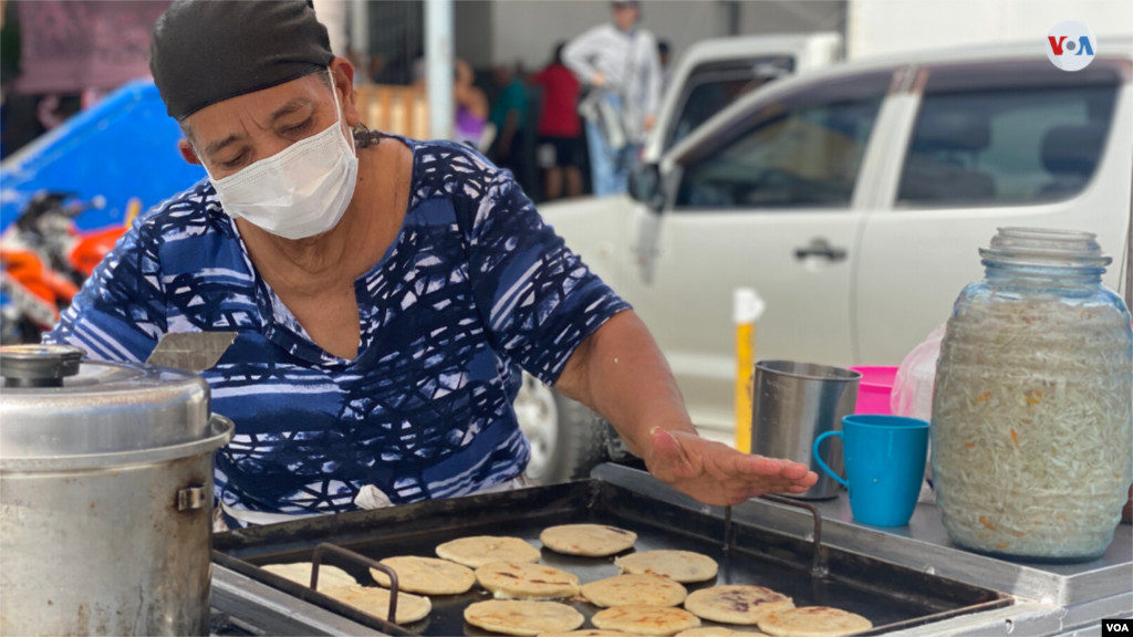 Una vendedora con mascarilla hace pupusas salvadoreñas en un mercado de Managua. Los trabajadores informales en esta ciudad afirman que no pueden dejar de vender pues no tendrían ingresos para sobrevivir. [Foto: Houston Castillo]