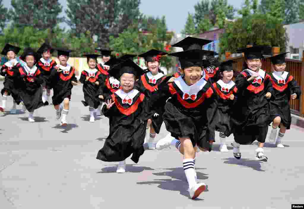 Children in gowns and mortarboards run with smiles during their kindergarten graduation ceremony in a kindergarten in Handan, Hebei province, China.