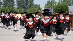 FILE - Children in gowns and mortarboards run with smiles during their kindergarten graduation ceremony in Handan, Hebei province, China, June 20, 2017.