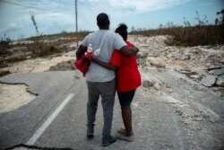 A couple embraces on a road destroyed by Hurricane Dorian, as they walk to the town of High Rock to try to find their relatives in the aftermath of Hurricane Dorian, in Grand Bahama, Bahamas, Sept. 5, 2019.