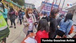 Largas filas para votar en Bolivia. En la foto, una ciudadana presenta el carné de identidad, indispensable para el ingreso al recinto de votación. Foto: Yuvinka Gozalves Avilés, VOA. Domingo 18 de octubre de 2020.