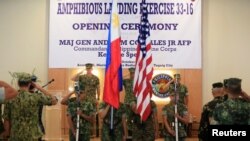 美国海军陆战队准将詹森（左）和菲律宾海军陆战队的少将科斯塔莱斯（中）在联合军事演习前在两国国旗前面敬礼（2016年10月4日）