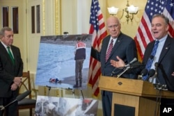 From right to left, Sen. Tim Kaine, D-Va., Sen. Patrick Leahy, D-Vt., and Sen. Dick Durbin, D-Ill., display the now-famous news photo of the lifeless body of a Kurdish child who drowned along with other refugees during a failed attempt to sail to the Greek island of Kos, during a press conference at the Capitol in Washington, Dec. 8, 2015.