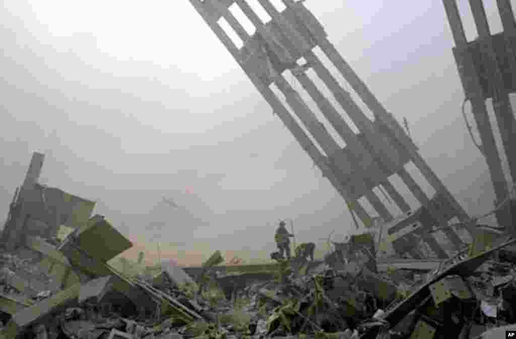 Firefighters are dwarfed by debris at the site of the World Trade Center in New York Tuesday, Sept. 11, 2001. Planes crashed into the upper floors of the World Trade Center towers minutes apart Tuesday morning collapsing both 110-story buildings. (AP Phot