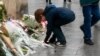 A boy lights a candle in front of a plaque paying tribute to 15 dead at a bar and restaurant in northern Paris, Nov. 13, 2016. (L. Bryant/VOA)