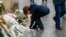 A boy lights a candle in front of a plaque paying tribute to 15 dead at a bar and restaurant in northern Paris, Nov. 13, 2016. (L. Bryant/VOA)