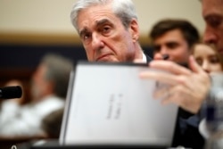 FILE - Former special counsel Robert Mueller checks pages in the report as he testifies before the House Judiciary Committee hearing on his report on Russian election interference, on Capitol Hill, July 24, 2019.