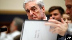 FILE - Former special counsel Robert Mueller checks pages in the report as he testifies before the House Judiciary Committee hearing on his report on Russian election interference, on Capitol Hill, July 24, 2019.