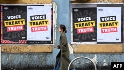 A woman walks past posters advocating for an Aboriginal voice and treaty ahead of an upcoming referendum, in Melbourne on Aug. 30, 2023.