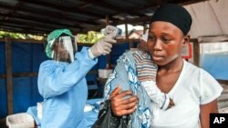 FILE - A woman has her temperature taken as part of Ebola prevention, prior to entering the Macauley government hospital in Freetown, Sierra Leone, Jan. 21, 2016. Neighboring Liberia has been declared free of the virus again. 