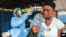 FILE - A woman has her temperature taken as part of Ebola prevention, prior to entering the Macauley government hospital in Freetown, Sierra Leone, Jan. 21, 2016. 