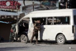 An Afghan security forces member inspects a bus carrying local TV station employees that hit a roadside bomb in Kabul, May 30, 2020.